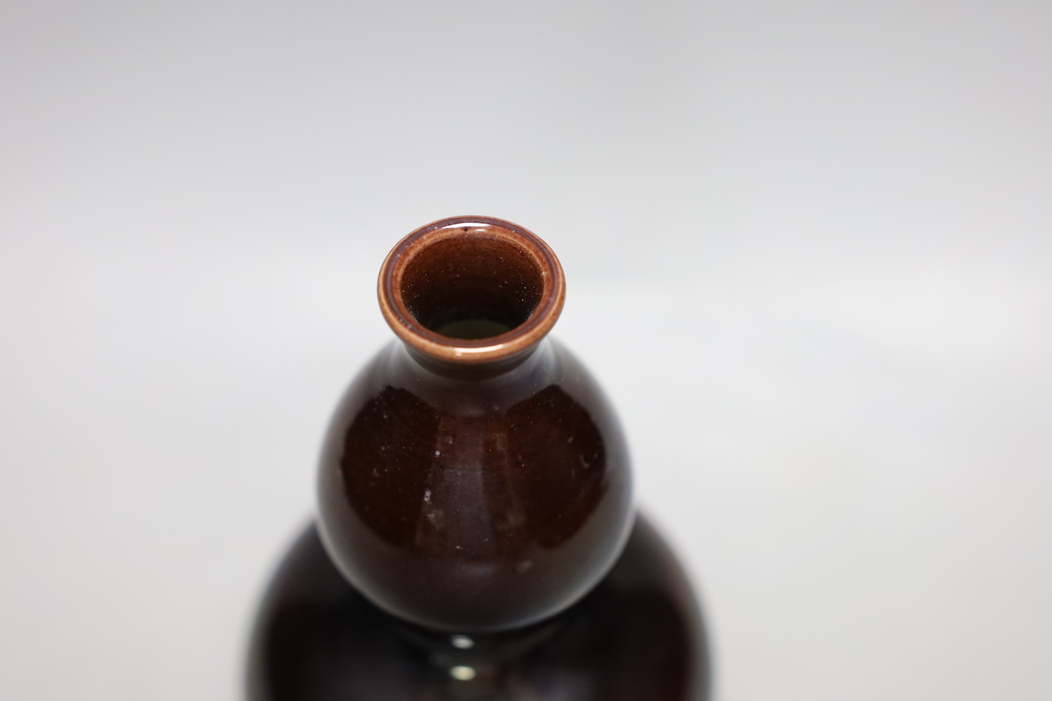 A Chinese brown monochrome double gourd vase (on stand). 19cm tall